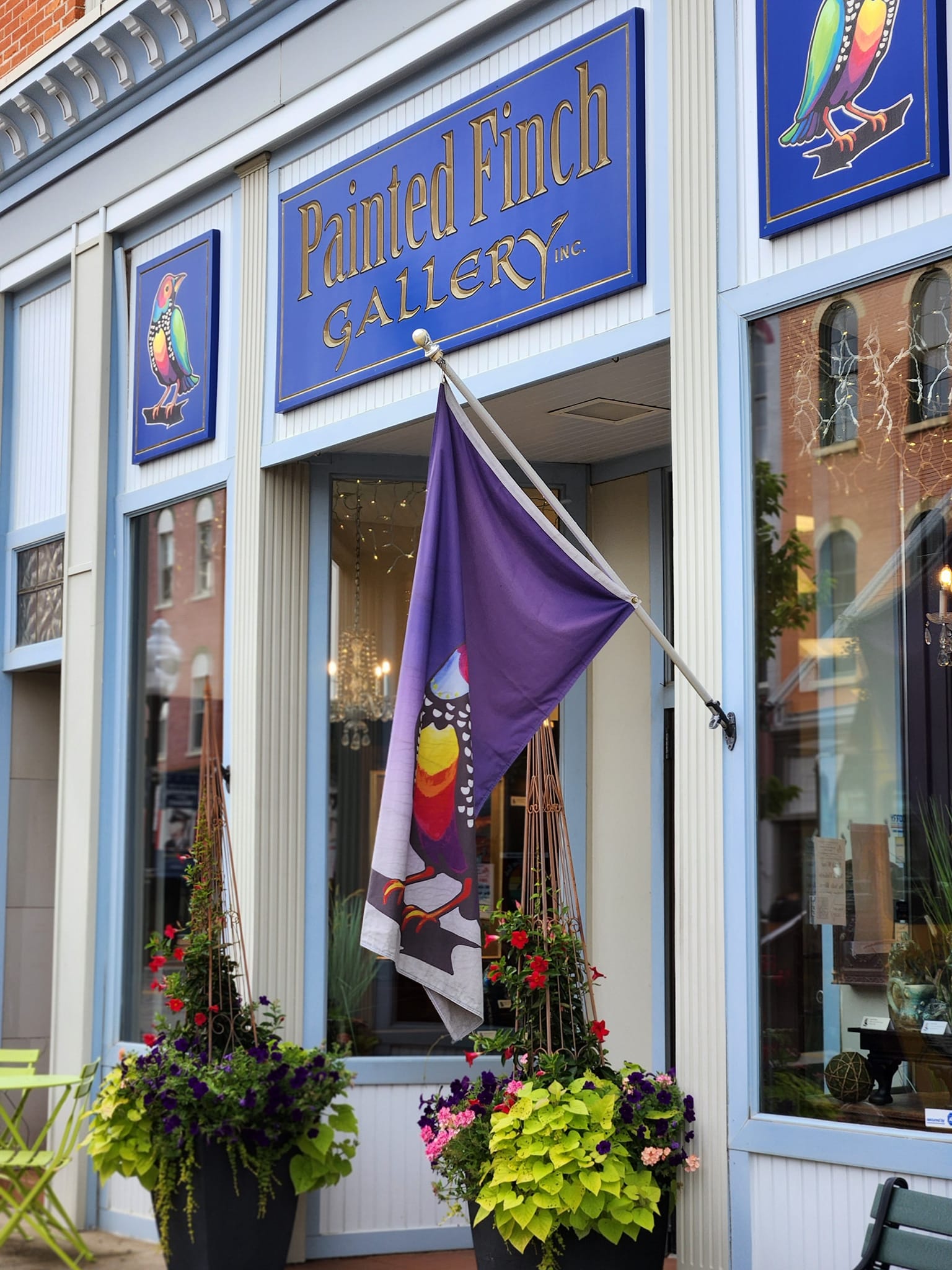 Painted Finch Gallery with a purple flag and decorative plants outside.